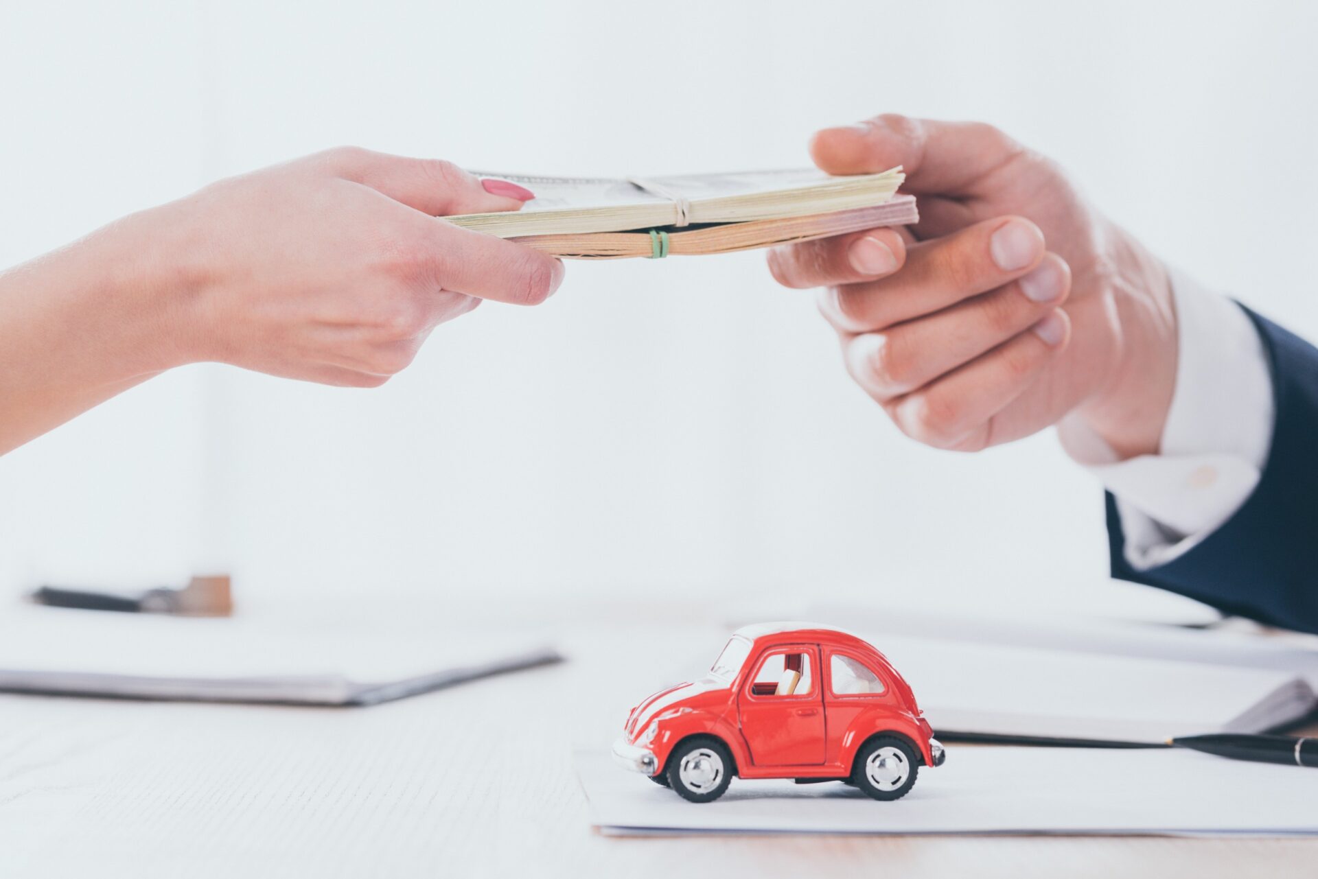 Person taking money from woman near red toy car