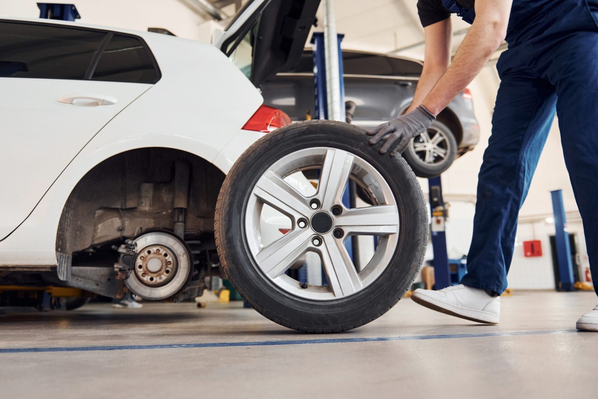 view of man in work uniform with car wheel indoors